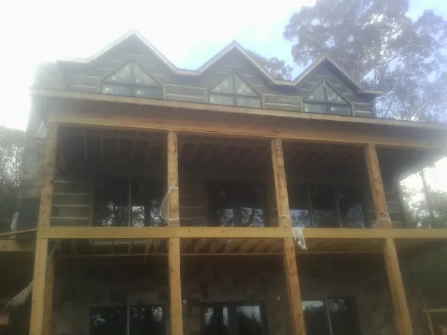 Dormers and porch framing on a large log home under construction — Roof Coating work by our crew in La Grange